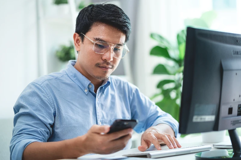 A men wearing glasses is sitting at a desk with a computer